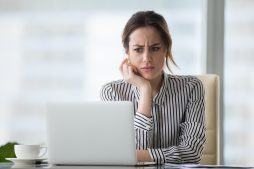 Verzweifelte Frau sitzt an Laptop
