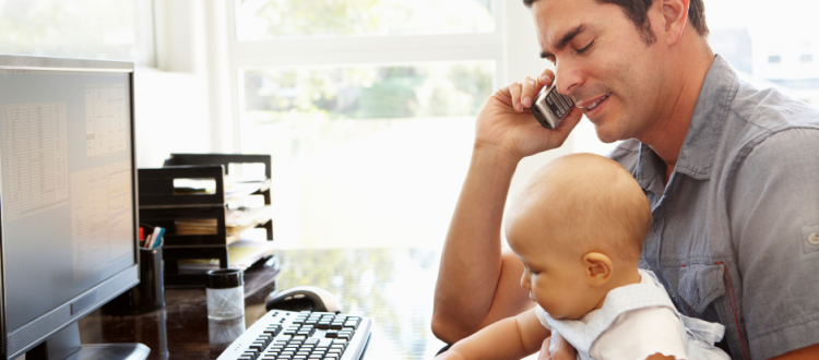 Elternzeit im Arbeitszeugnis: Vater mit Baby am Schreibtisch