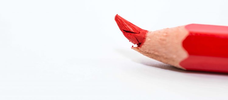 Roter Stift mit abgebrochener Spitze als Sinnbild für zu viele Rechtschreibfehler im Arbeitszeugnis