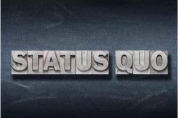 Schriftzug STATUS QUO auf grauem Hintergrund
