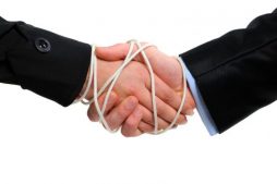 Zwei Männer geben sich die Hand. Ihnen sind die Hände gebunden.